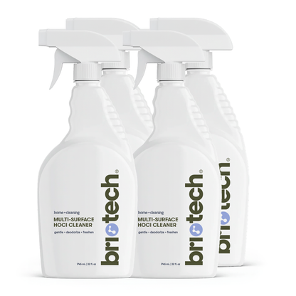 Four white spray bottles of Multi-Surface HOCl Cleaner are arranged in two rows, with their front labels clearly visible in black and blue text. This effective cleaner is perfect for cleaning hard surfaces and eliminating odors throughout your home or workspace.