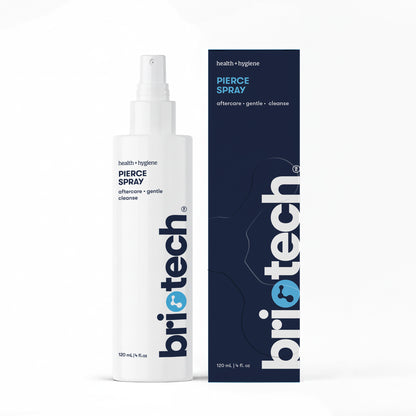 A white 120 mL (4 fl oz) Pierce Spray bottle stands by its box; both feature blue and gray text with a modern design. The spray delivers a soothing mist for gentle post-piercing care.