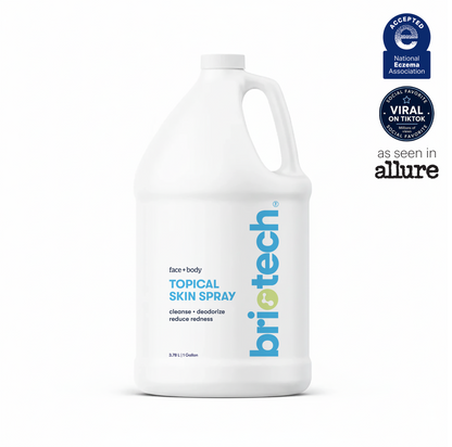 A white gallon bottle labeled Topical Skin Spray features blue and gray text. Three badges at the top right showcase endorsements and media mentions, including recognition from the National Eczema Association and Allure. This soothing spray is specially formulated to calm irritation and promote healthier-looking skin.